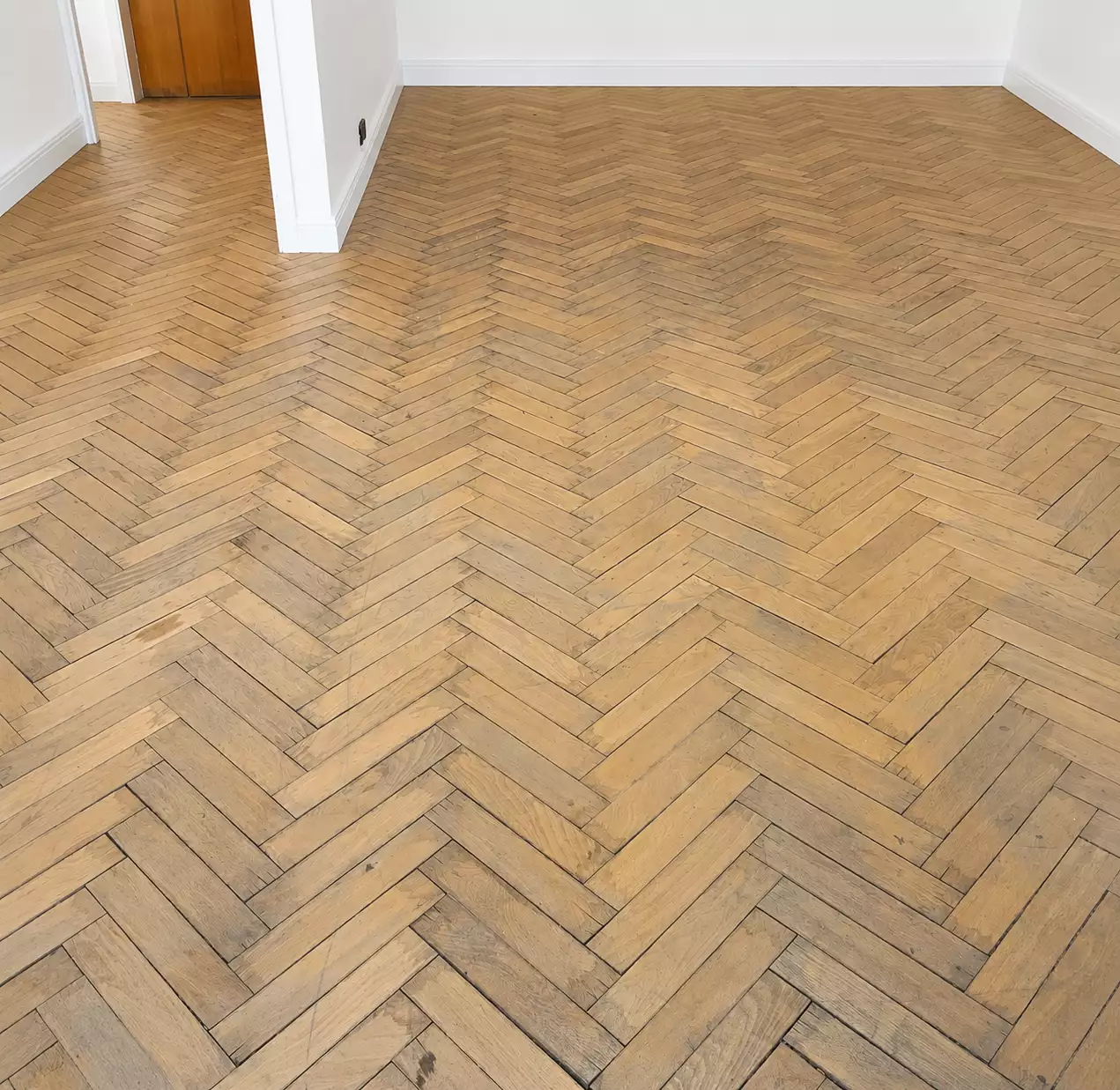Parquet chevron marqué par l'usure des passages